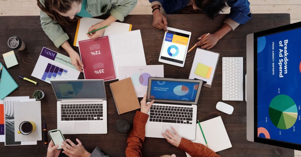 A diverse team collaborating on digital marketing strategies at a desk, using laptops and tablets.